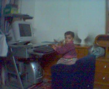 A young child sitting at a desk in front of a CRT monitor and keyboard