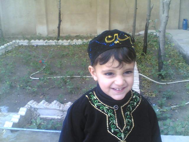 The same boy in the same garden, smiling at the camera